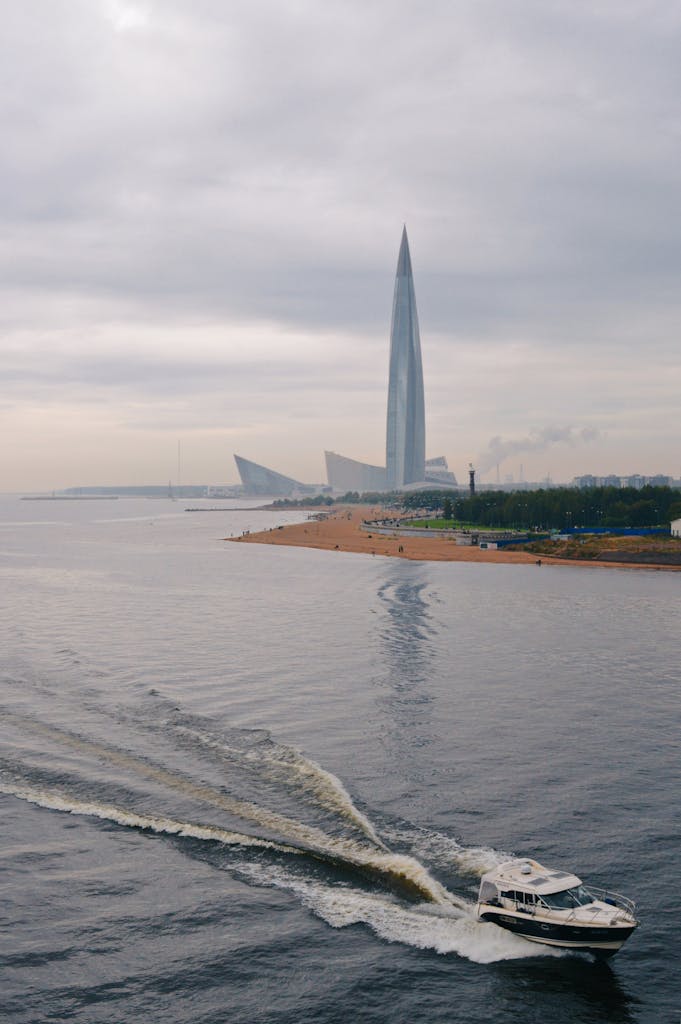 Una barca sul fiume con il grattacielo del Lakhta Center sullo sfondo, sotto un cielo nuvoloso a San Pietroburgo, Russia.