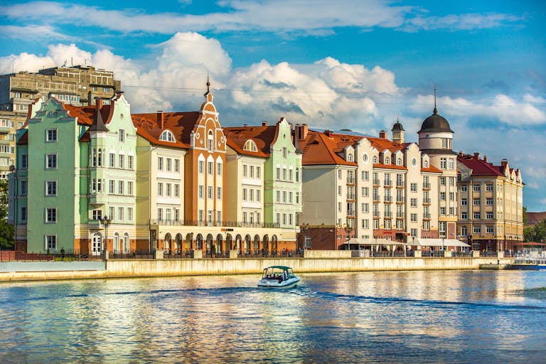 Colorful historic waterfront buildings and boat on Pregolya River, Kaliningrad.