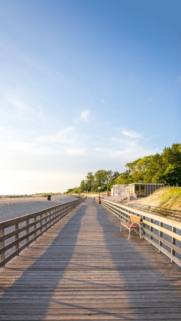 Scenic wooden boardwalk leading to a sandy beach under a clear blue sky in Kaliningrad, Russia.