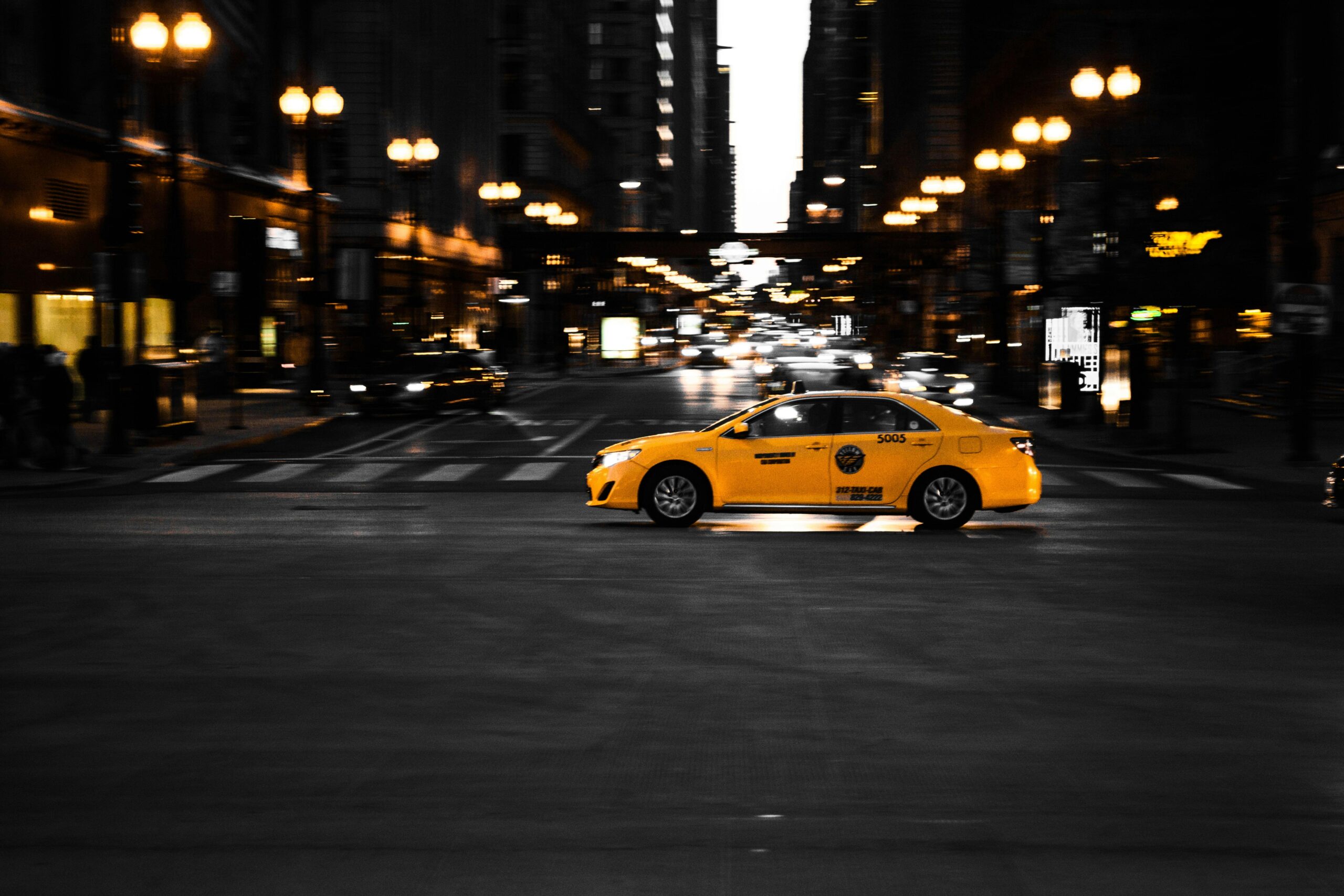 Taxi giallo in movimento su una strada illuminata di notte con effetto motion blur