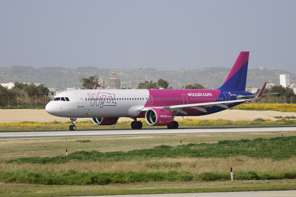 A Wizz Air Airbus A321 airplane taxis on the runway with a landscape background