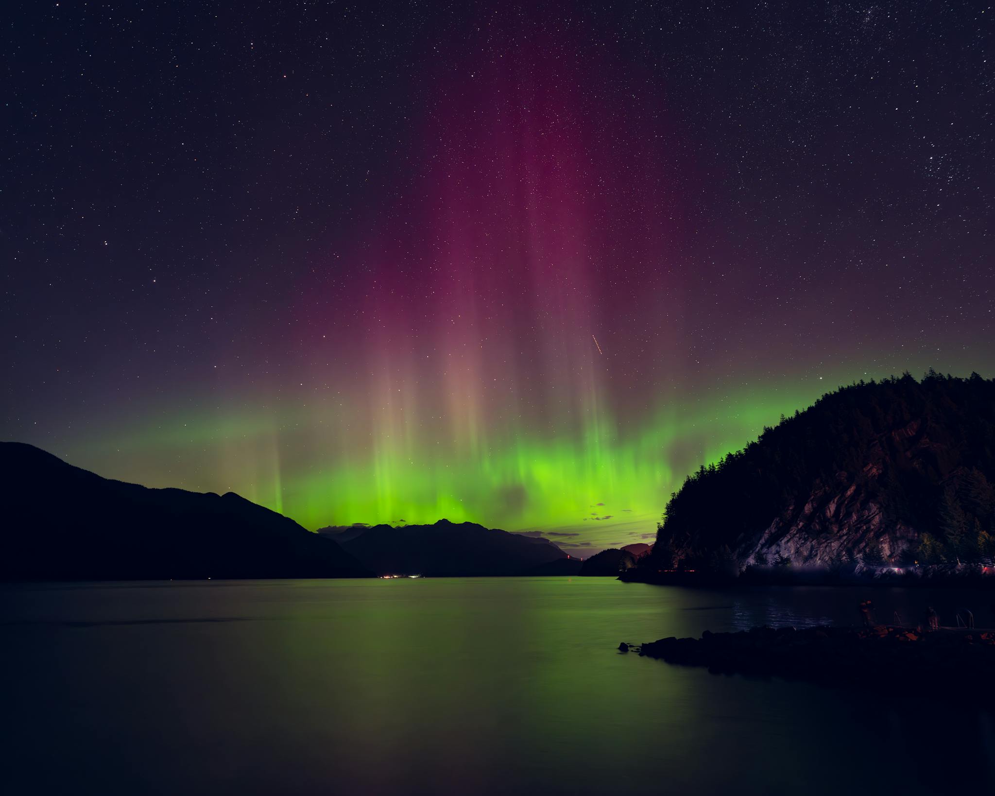 Aurora boreal reflejada en un lago bajo un cielo estrellado