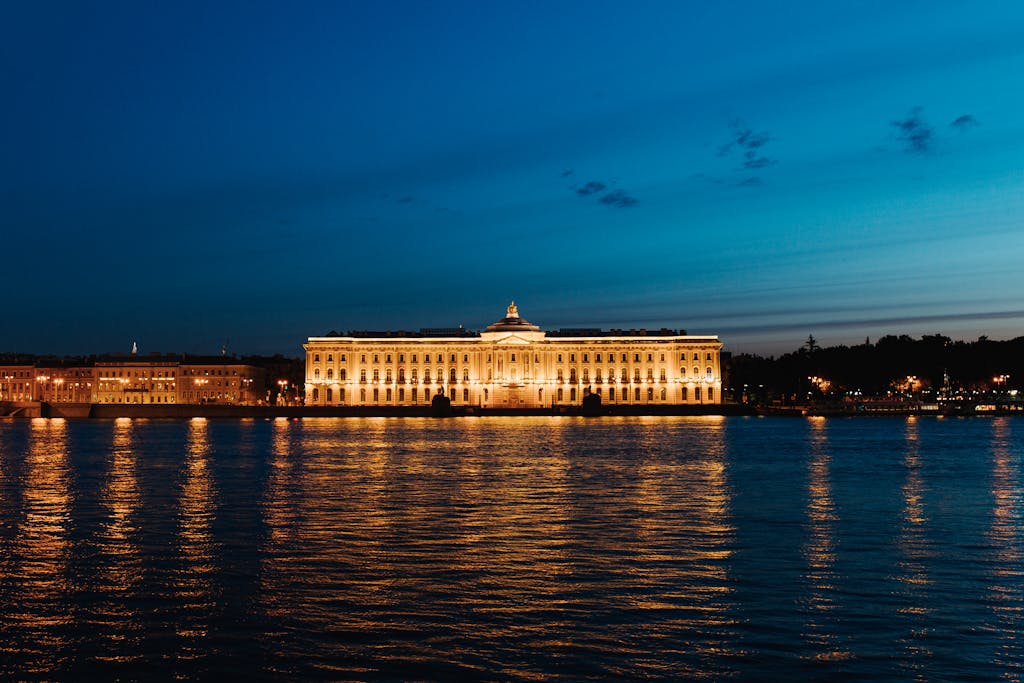 Beleuchtete Kaiserliche Akademie der Künste am Flussufer in Sankt Petersburg in der Dämmerung