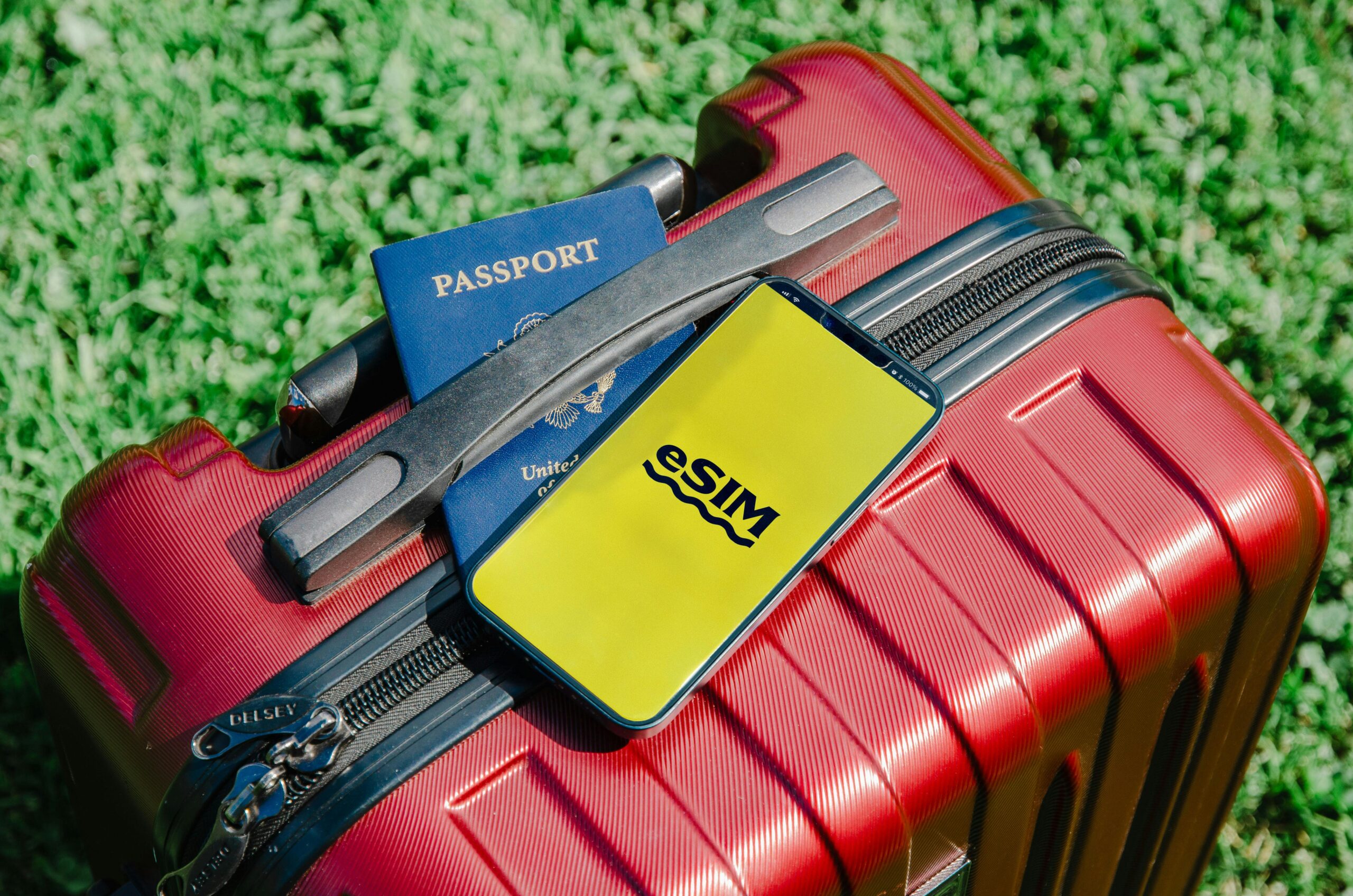 Móvil junto a un pasaporte y una maleta de viaje, ilustrando los controles fronterizos rusos a dispositivos electrónicos