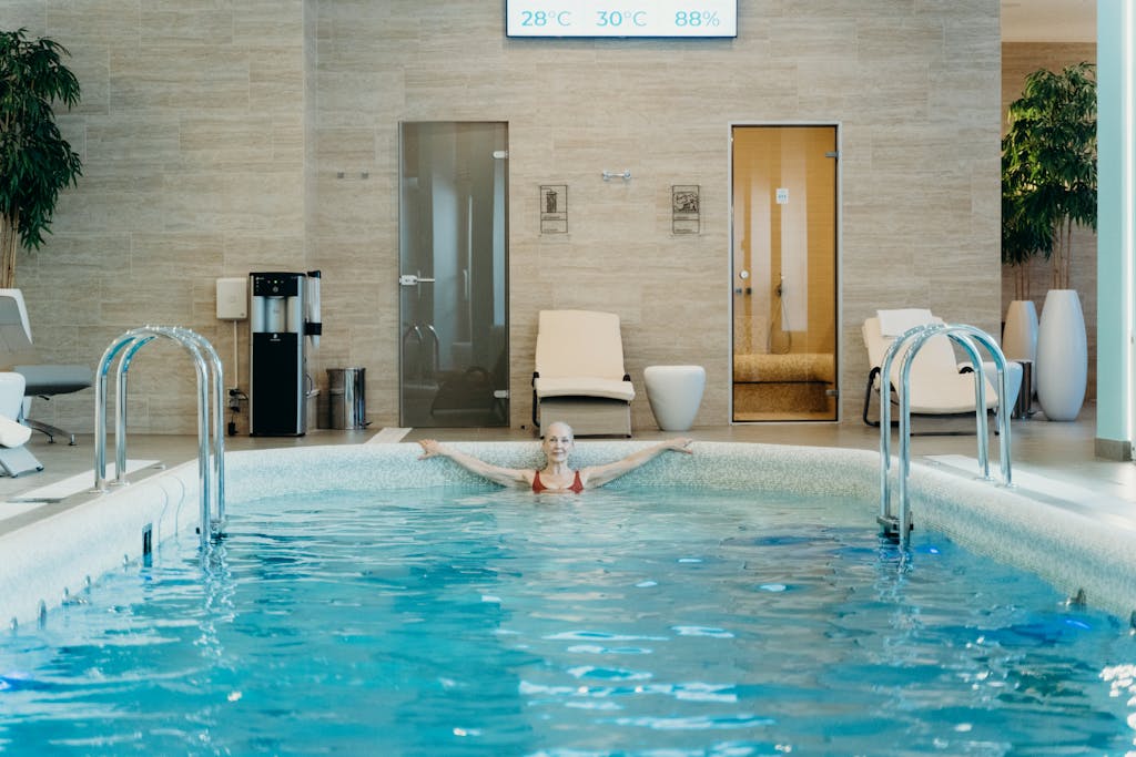Staršia žena si užíva pokojné plávanie v krytom bazéne spa s moderným vybavením.