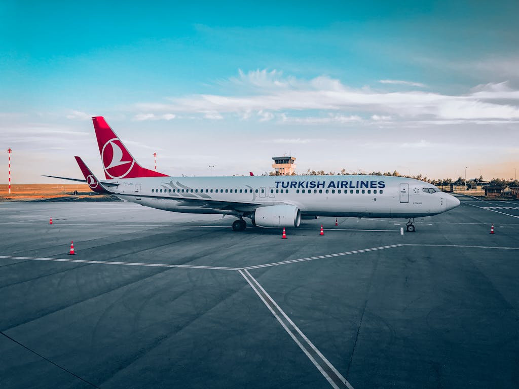 Turkish Airlines aircraft parked at the airport runway under a cloudy blue sky, early morning scene