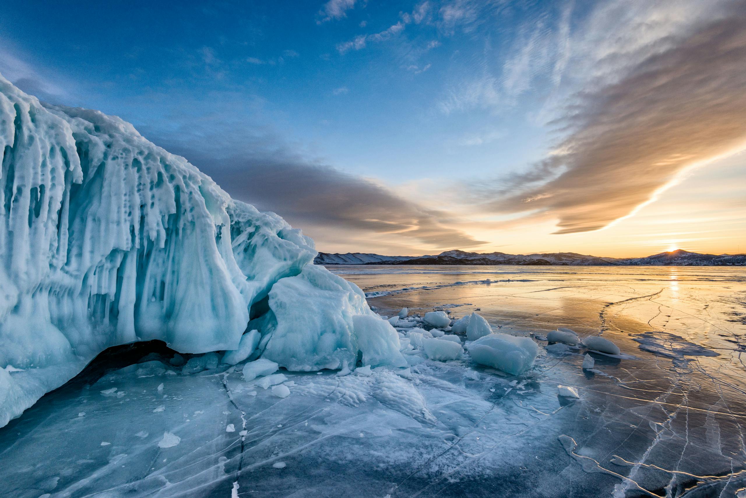 Atemberaubender Blick auf den gefrorenen Baikalsee mit Eisformationen unter einem leuchtenden Sonnenuntergangshimmel
