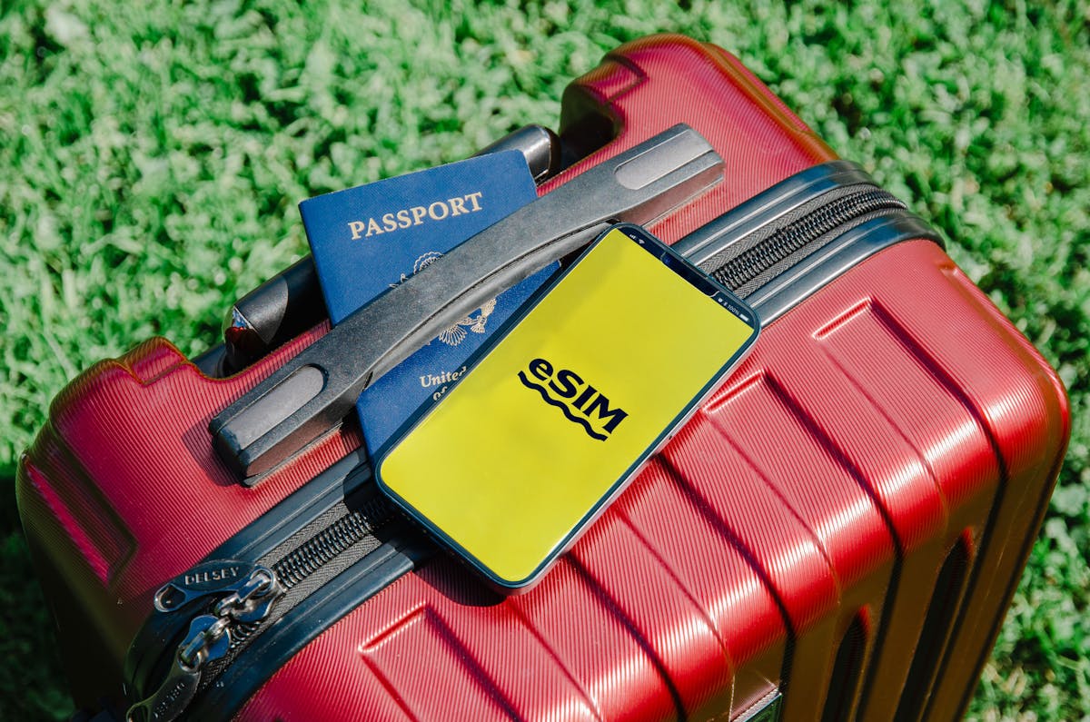 Roter Koffer mit einem Smartphone, das eine eSIM zeigt, und einem Reisepass, bereit für eine Russlandreise
