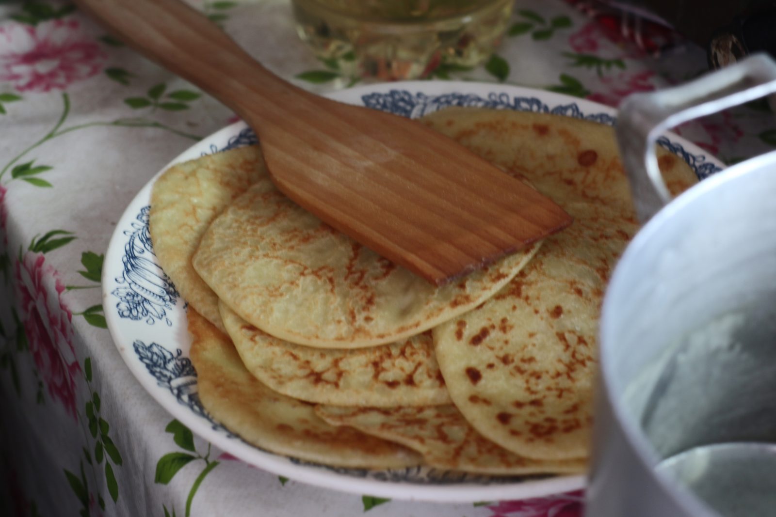 Plato de blinis rusos recién hechos sobre un mantel de flores